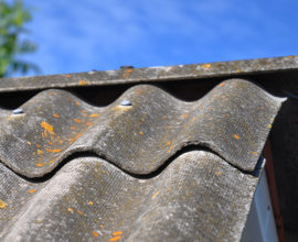 Blue sky over the dangerous asbestos old roof tiles